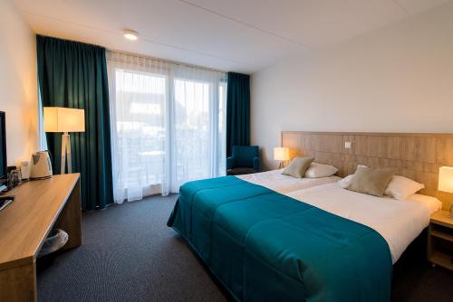 ein Hotelzimmer mit einem großen Bett und einem Schreibtisch in der Unterkunft Hotel Nes in Nes