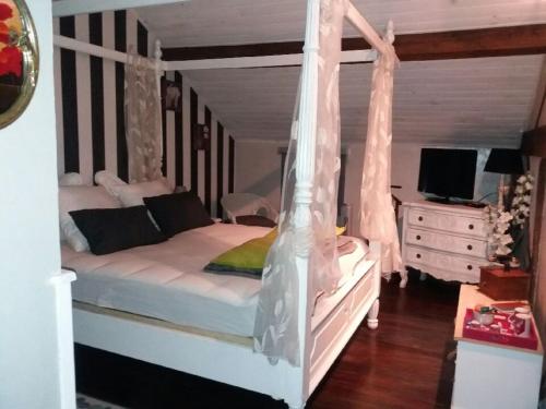 une chambre avec un lit blanc à baldaquin dans l'établissement Chez les Dom’s, à Sainte-Cécile