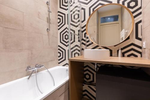 ein Badezimmer mit einer Badewanne, einem Spiegel und einem Waschbecken in der Unterkunft DIFY Art Déco - Charpennes in Villeurbanne