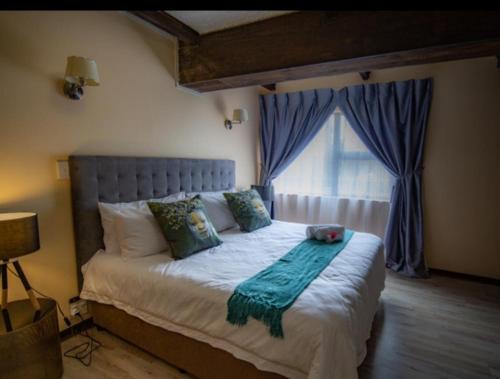 1 dormitorio con 1 cama grande y ventana en BougainVilla Guest House en King Williamʼs Town