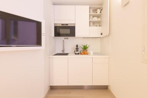 a kitchen with white cabinets and a flat screen tv at Traverse Des Artistes in Cannes