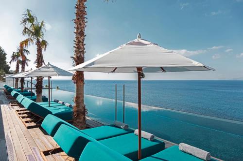 a row of chairs and umbrellas next to a swimming pool at Mitsis Summer Palace in Kardamaina