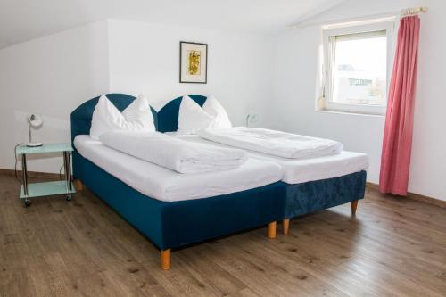 una cama azul con almohadas blancas en una habitación en Wohnen in Innsbruck, en Innsbruck