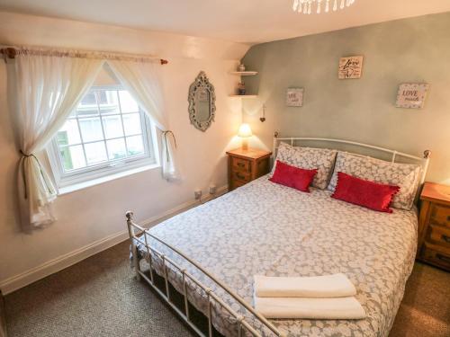 sypialnia z łóżkiem z czerwonymi poduszkami i oknem w obiekcie Wee Cot w mieście Sandown