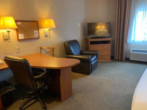 a hotel room with a table and a chair and a television at Candlewood Suites Jonesboro by IHG in Jonesboro