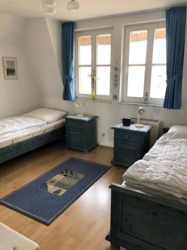 a bedroom with two beds and two windows at Refugium Raabenhorst im Landhaus am Haff in Stolpe auf Usedom