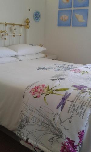 a bed with a blanket with flowers on it at Vlei Studio in Bettyʼs Bay