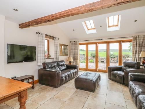 a living room with leather furniture and a flat screen tv at Rose Hips Barn in Chorley