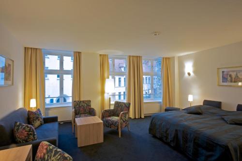 ein Hotelzimmer mit einem Bett, Stühlen und Fenstern in der Unterkunft Hotel Bremer Hof in Lüneburg