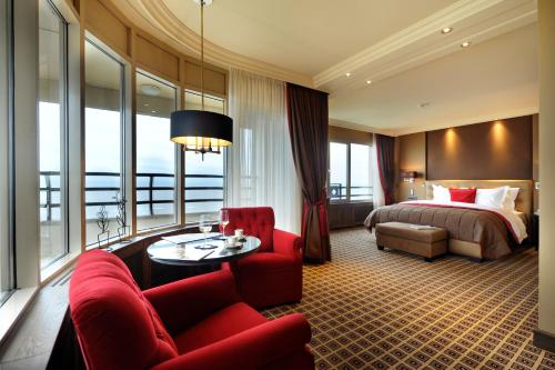 um quarto de hotel com uma cama e um sofá vermelho em Grand Hotel Huis ter Duin em Noordwijk aan Zee