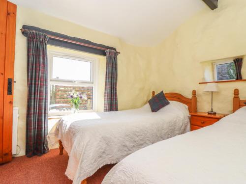 a bedroom with two beds and a window at Bowling Green Cottage in Redruth