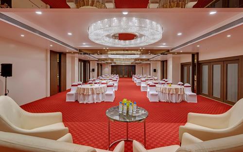 un salón de banquetes con mesas y sillas blancas y una lámpara de araña en The Fern, Kolhapur, en Kolhapur