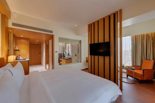 Un dormitorio con una cama blanca y una sala de estar. en The Fern, Kolhapur, en Kolhapur
