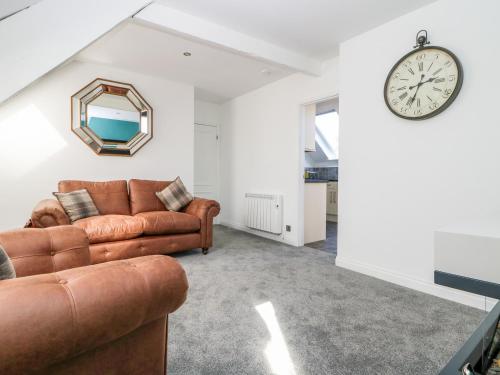 a living room with a couch and a clock on the wall at 2 Rodgers Mews in Malton