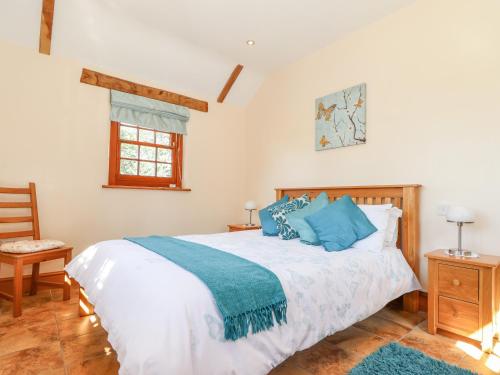 a bedroom with a large white bed with blue pillows at Valley View in Helston