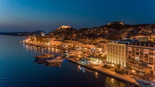 una città illuminata di notte con barche in acqua di Apartments Guberina a Šibenik