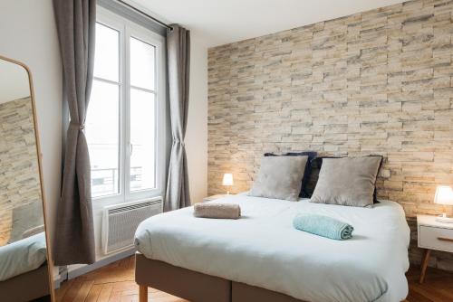 a bedroom with a large bed with a brick wall at DIFY Cosy - Centre Ville in Lyon