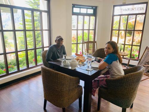 Un uomo e una ragazza seduti a un tavolo di Sherwood Cottage a Nuwara Eliya