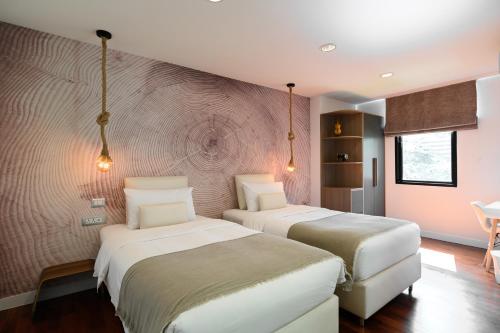two beds in a hotel room with lights on the wall at Benviar Tonson Residence in Bangkok