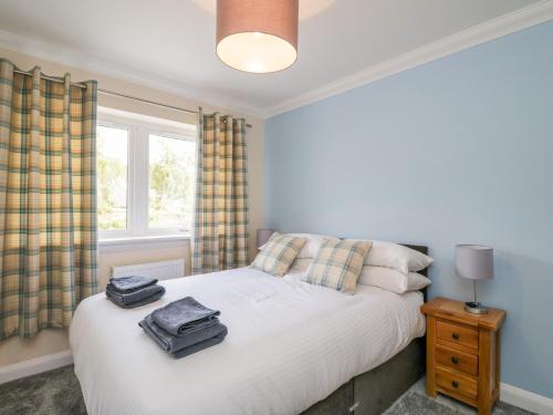 a bedroom with a white bed and a window at Emsa House in Spean Bridge
