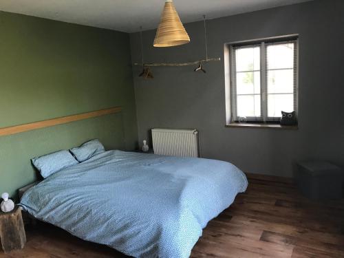 a bedroom with a blue bed and a window at Chez sandrine in Mouhet