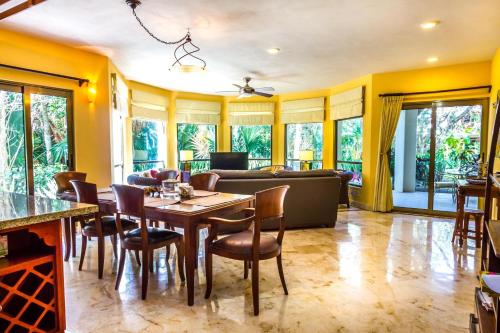 comedor con mesa, sillas y sofá en Paseo del Sol Coral A 105 condo, en Playa del Carmen