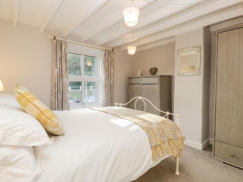 una camera da letto con un letto bianco e una finestra di Rosie Cottage a Filey