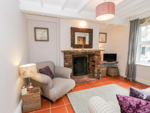 a living room with a fireplace and a chair at Rosie Cottage in Filey