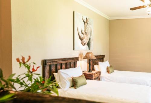 a bedroom with two beds and a table with a lamp at Farmstay Okakeua in Okahandja