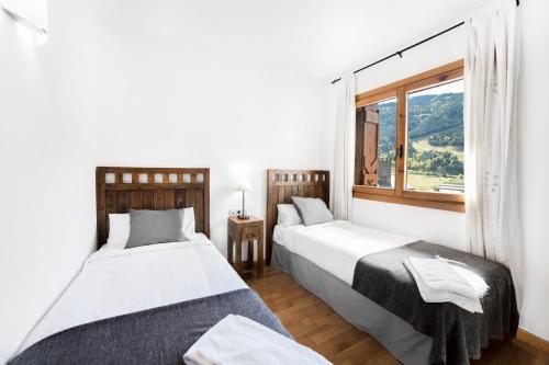 2 camas en una habitación con ventana en Esquirol Apartments, en El Tarter