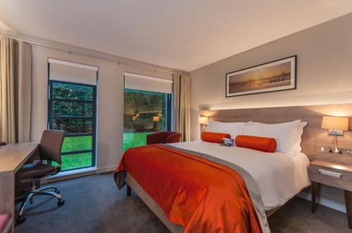 a bedroom with a bed and a desk and a window at Greenlands Hotel in Henley on Thames