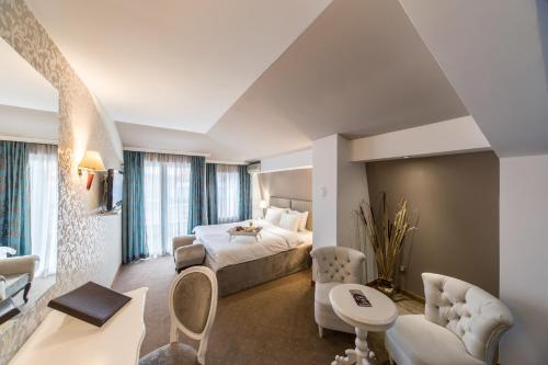ein Hotelzimmer mit einem Bett und einem Wohnzimmer in der Unterkunft Garni Hotel President de Luxe in Kragujevac