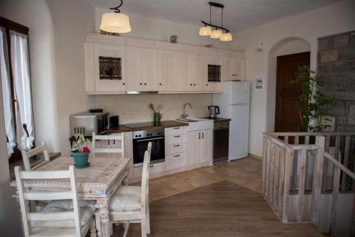 una cocina con armarios blancos y una mesa con sillas. en Grand View Rhea, en Mithimna
