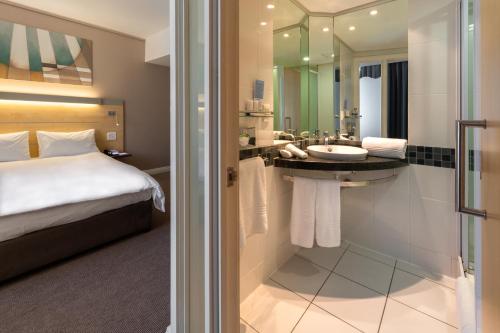 a hotel room with a bed and a bathroom with a sink at Holiday Inn Express Cape Town City Centre by IHG in Cape Town