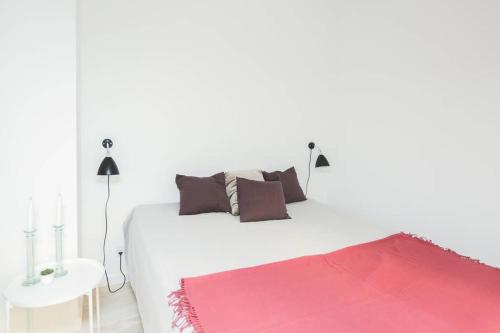 a white bed with brown pillows and a red rug at Exclusive and central - Private roof top terrace! in Copenhagen