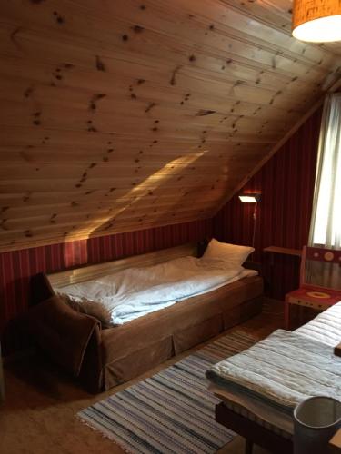 a bed in a room with a wooden ceiling at Christinagården Guesthouse in Ramsele