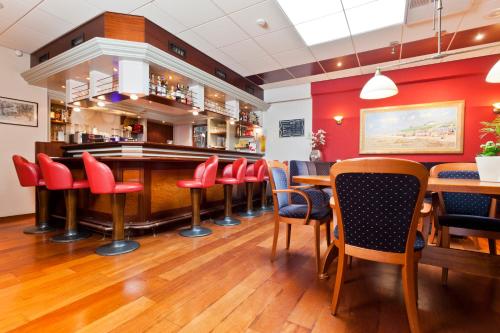 un bar dans un restaurant avec des murs et des chaises rouges dans l'établissement Hotel the Wigwam, à Domburg