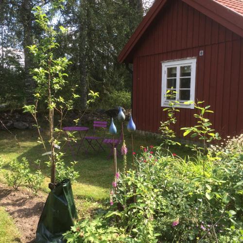 a garden with a red house and a picnic table at Stensholms Trädgård in Nässjö