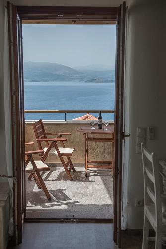 a door leading to a balcony with a table and chairs at Grand View Rhea in Mithymna