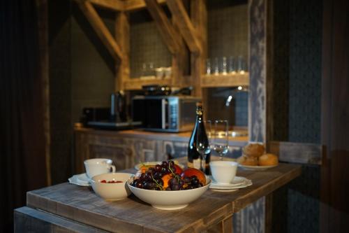 a table with a bowl of fruit and a bottle of wine at Aparthotel MyCologne in Cologne