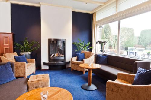 ein Wohnzimmer mit einem Sofa, Stühlen und einem Kamin in der Unterkunft Hotel the Wigwam in Domburg