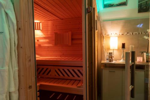 a sauna in a bathroom with a red wall at Hotel & Café Strandeck in Prerow