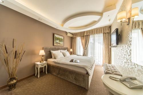 a bedroom with a bed and a television and a desk at Garni Hotel President de Luxe in Kragujevac