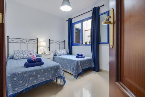 - une chambre bleue avec 2 lits et une fenêtre dans l'établissement El Rincón de Famara, à Famara