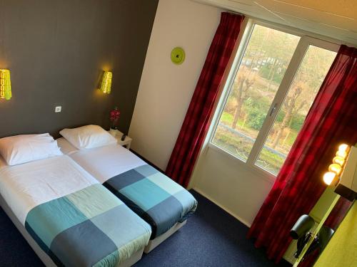 a bedroom with a bed and a large window at Hotel Oorsprongpark in Utrecht