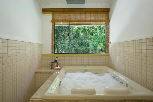 a bath tub in a bathroom with a window at Eco Resort Hotel Villa São Romão in Lumiar