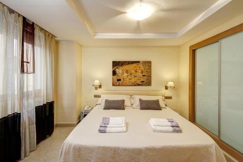 Un dormitorio con una cama grande con toallas. en Apartamentos Turísticos Centro, en Granada