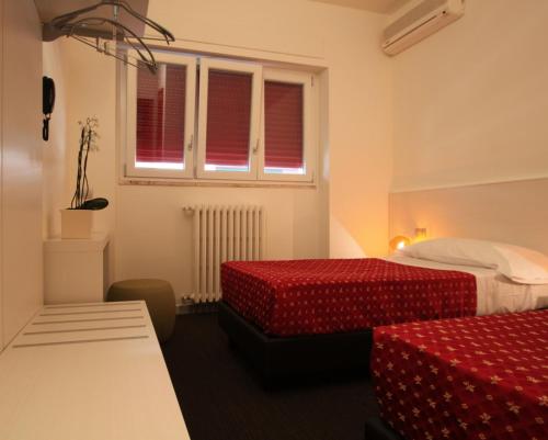 a hotel room with two beds and a window at Hotel Firenze in Saronno