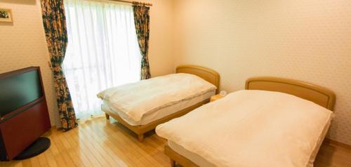 佐渡市的住宿－Guest house Third Place，客房设有两张床、一台电视和一扇窗户。
