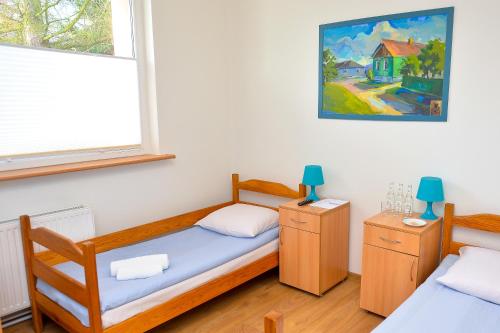 a bedroom with two beds and a painting on the wall at Dom św. Józefa in Szczecin